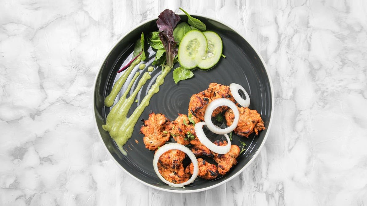 Sizzling tandoori chicken tikka garnished with mint chutney