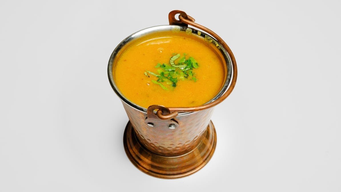 Yellow dal tadka served in traditional copper balti