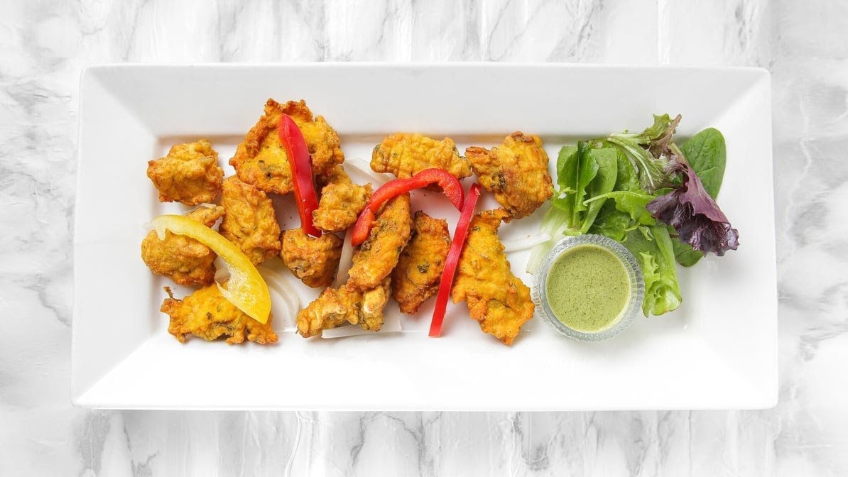 Golden crispy Fish Pakoras plate with mint chutney