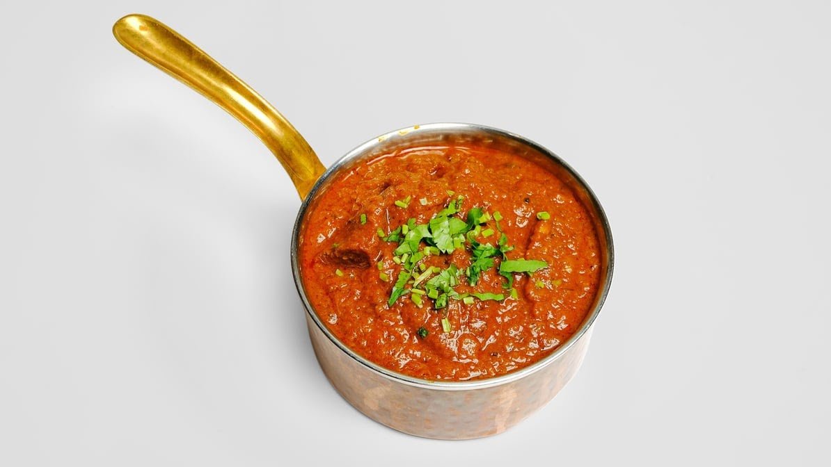 Rich slow-cooked Lamb Curry in brass pan