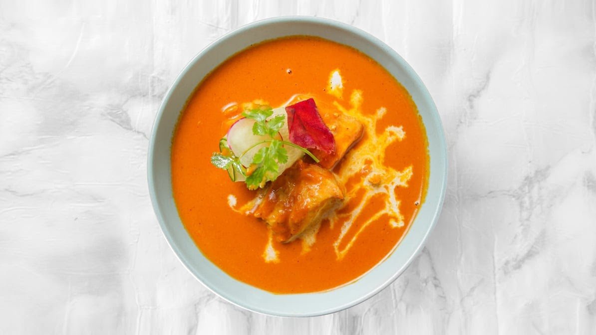 Rich creamy Butter Chicken garnished with cream and fresh coriander
